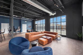 A modern office space with blue chairs and orange couches.at Plant 1 Lofts, N. Newton, IA  